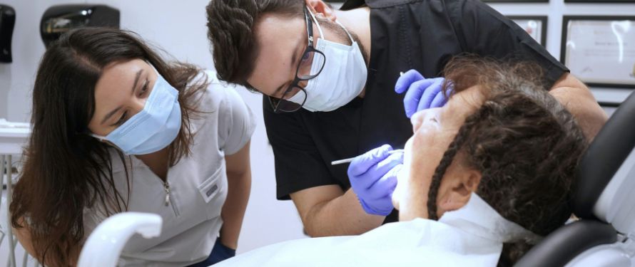 emergency dentist muskegon . Dentist treating patient during a dental emergency—urgent dental care exam with assistant observing.