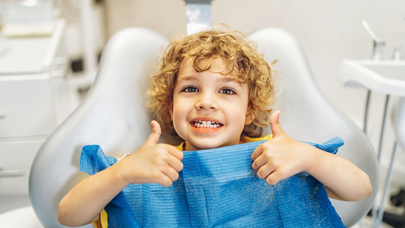 Your Child’s First Dental Visit Happy child at family dentist in Muskegon giving thumbs up during first dental visit